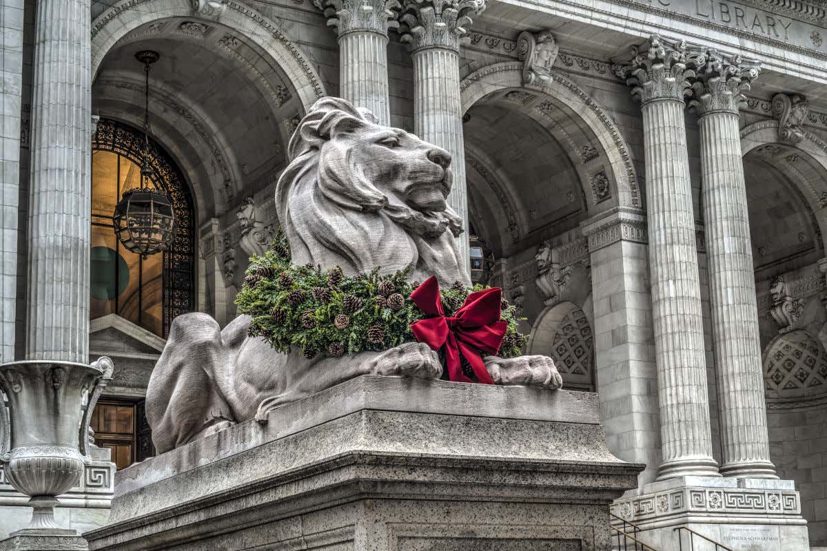 León de piedra decorado con una guirnalda de Navidad frente a la entrada de la Biblioteca Pública de Nueva York