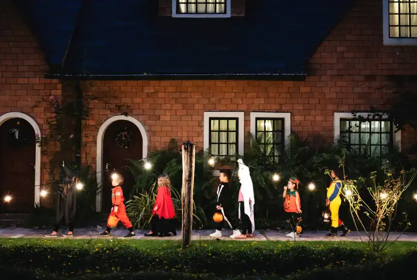 Enfants déguisés lors de la nuit d'Halloween se promenant dans une rue entre plusieurs maisons