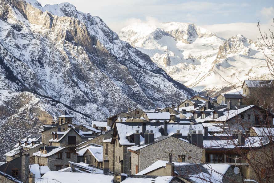 Paisajes nevados de un pueblo, con unas montañas de fondo