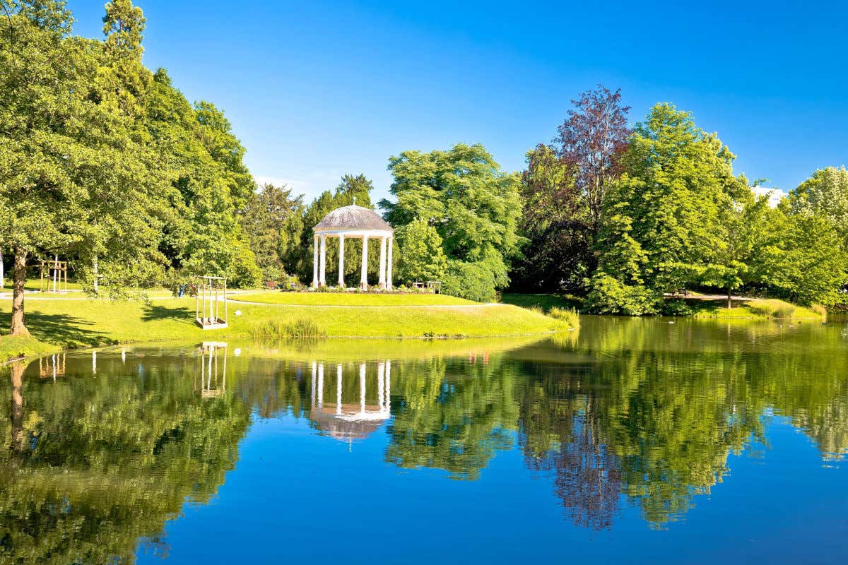 Un lago rodeado de vegetación y con un templete en su orilla en el parque de l'Orangerie de Estrasburgo