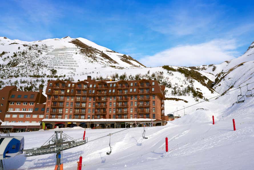 Hotel de montaña junto a los telesillas de una pista de esquí cubierta de nieve