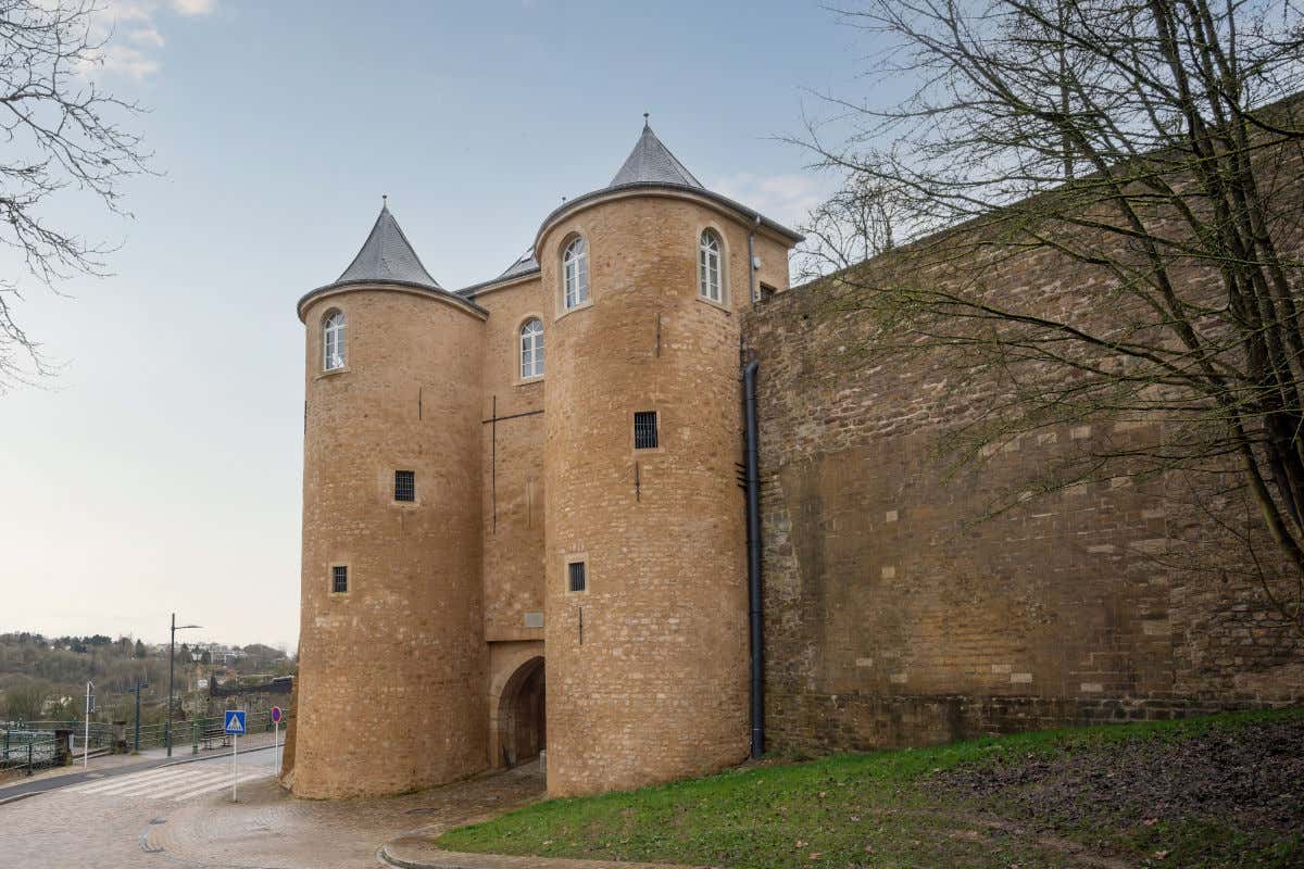 Antigo pórtico de pedra, encimado por duas torres e junto a uma muralha