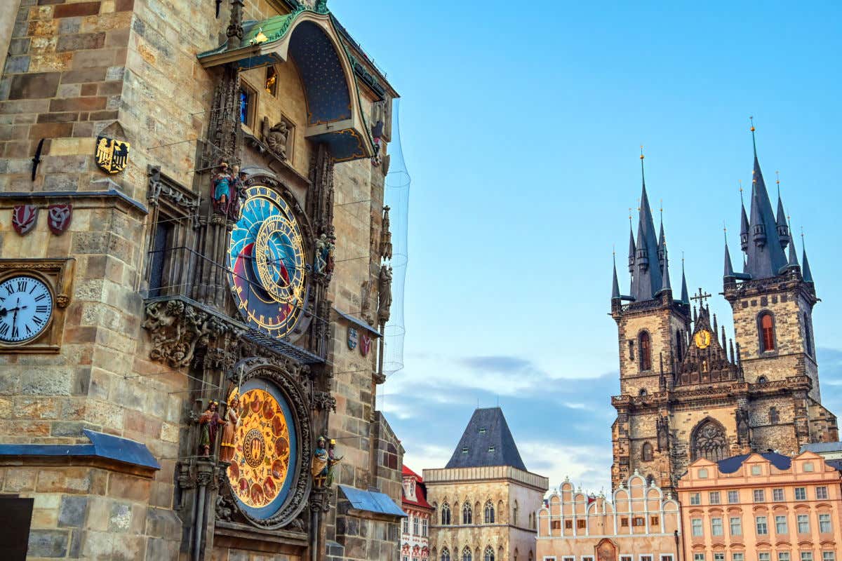 O Relógio Astronômico de Praga, com várias esculturas coloridas, em frente à fachada da Igreja de Týn