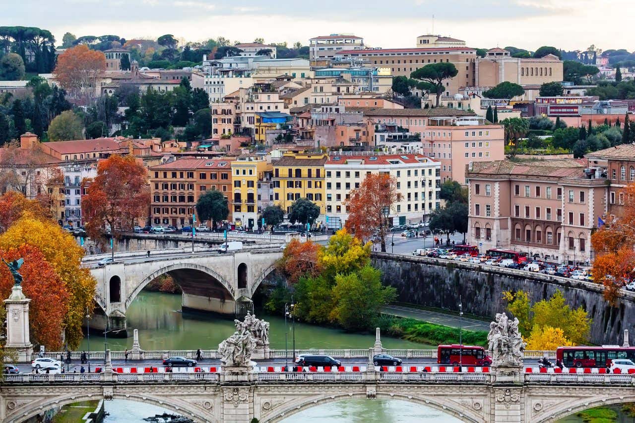 An aerial view of Rome with colourful buildings, viaducts, cars and trees in autumn.