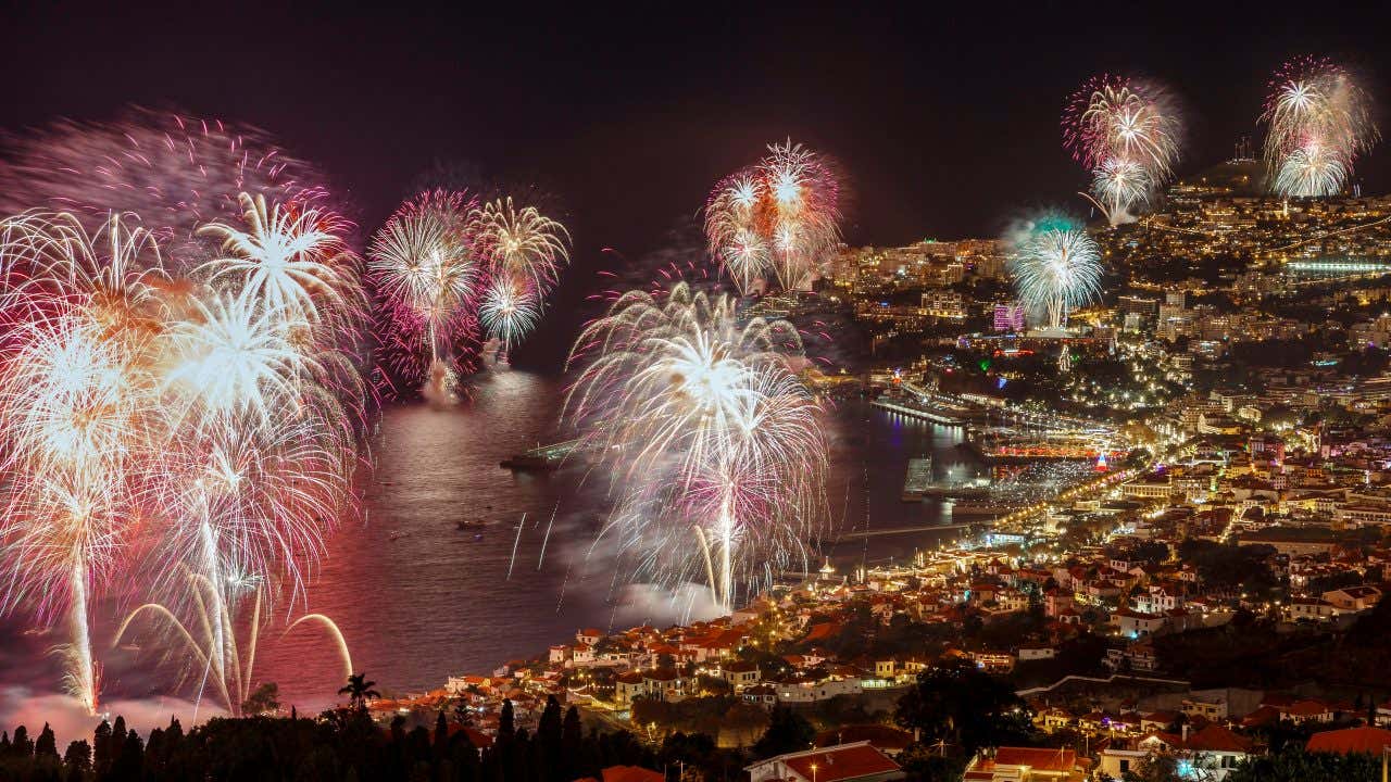 Foto notturna di una città costiera italiana illuminata da un gran numero di fuochi d'artificio