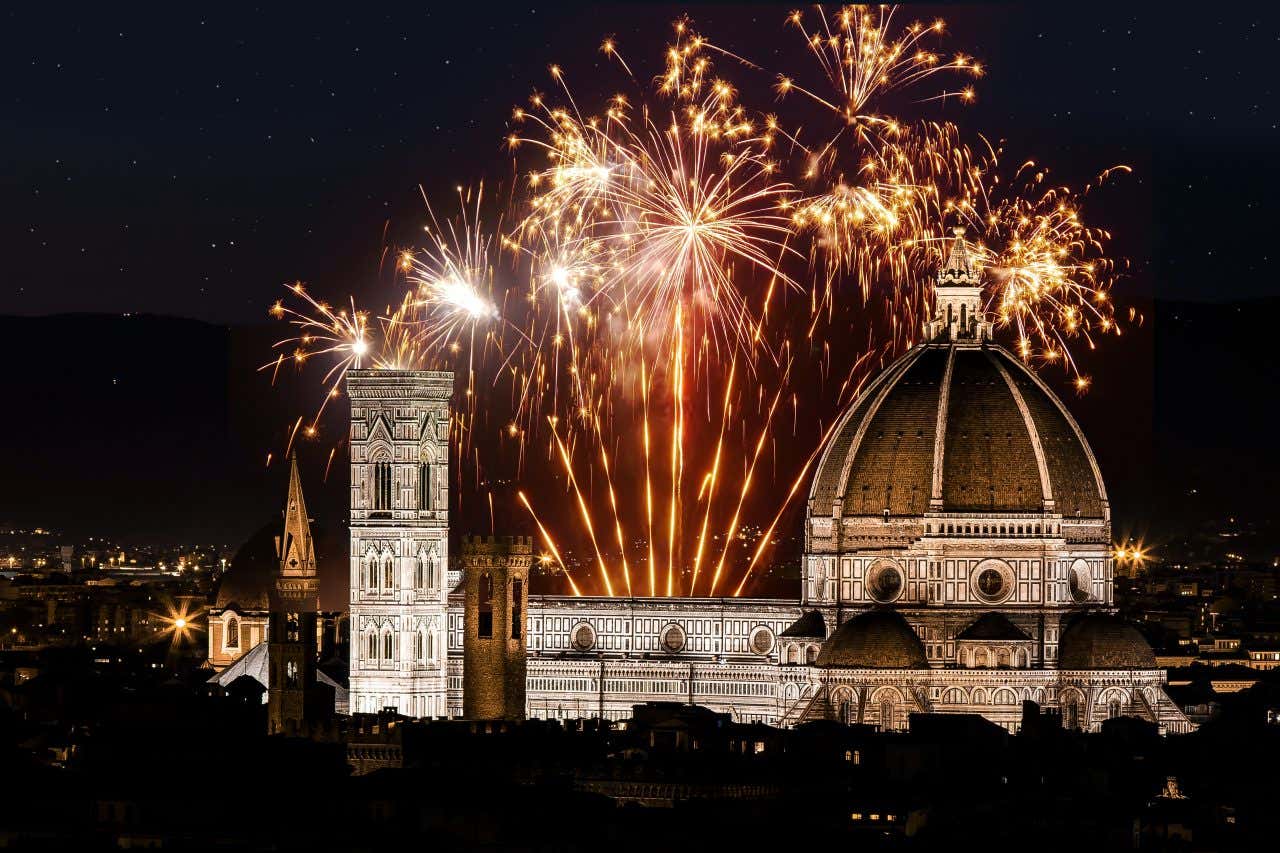 Il duomo di Firenze, con il suo campanile di Giotto e l'imponente cupola, di notte, illuminato da una serie di fuochi d'artificio color oro