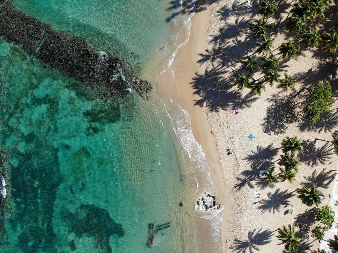 El Escambrón Beach as seen from above, with some tourists on the sand.