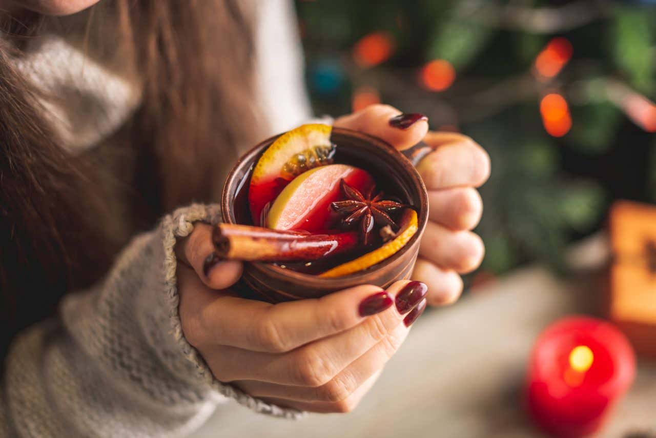 Une femme tenant un vin chaud, la boisson typique des marchés de Noël