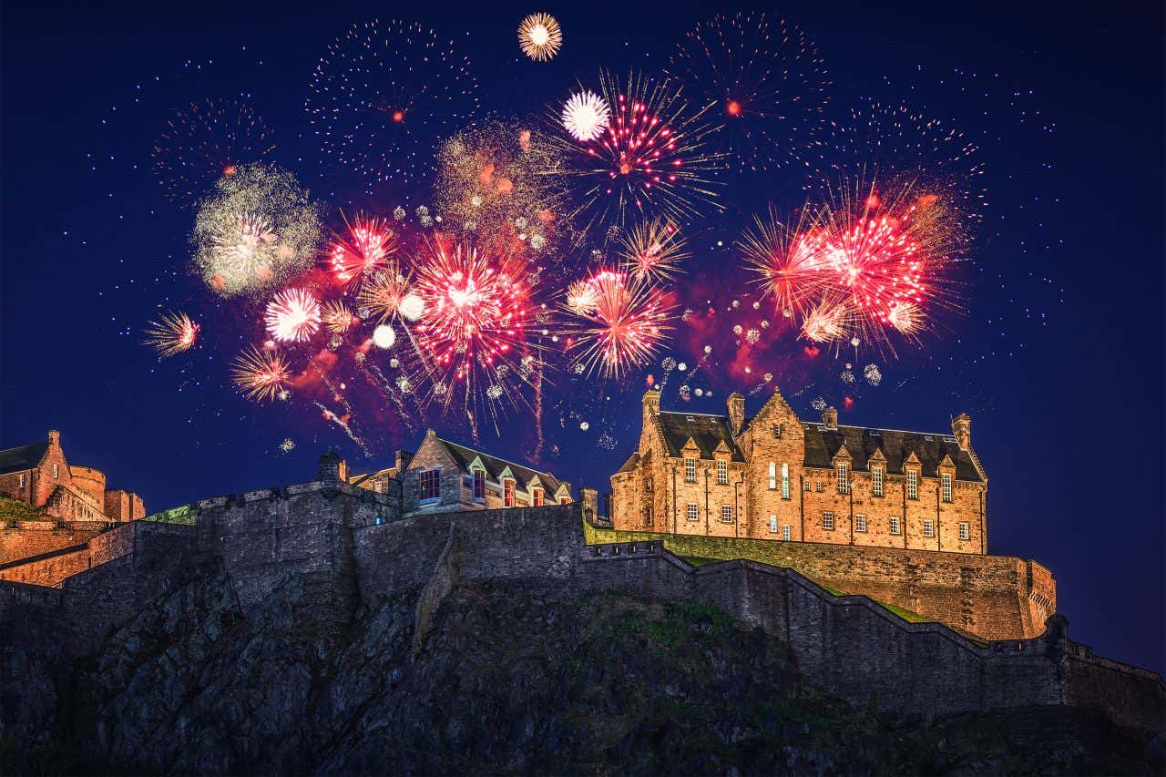 Il castello di Edimburgo in cima a una collina di notte illuminati da un gran numero di fuochi d'artificio