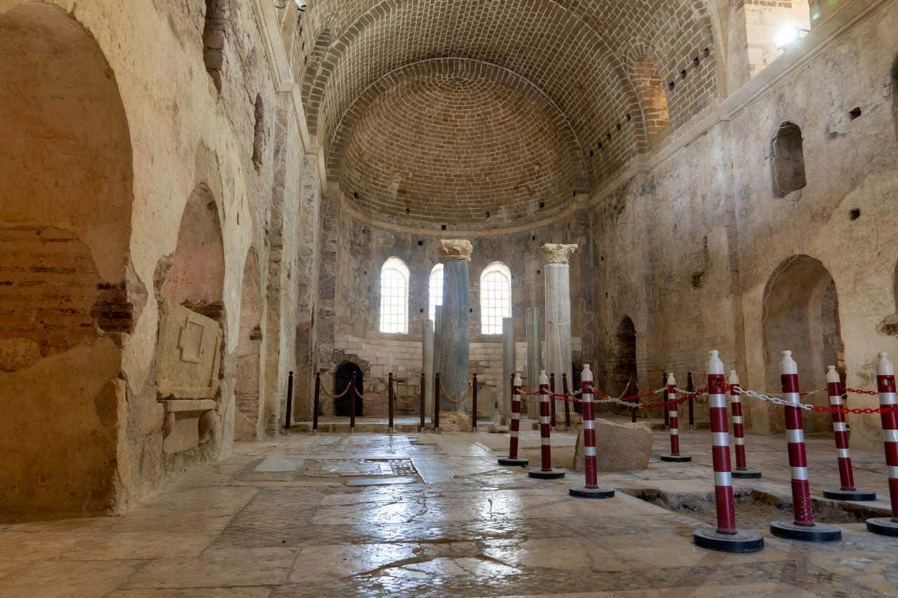 Vista dell'interno della chiesa di San Nicola in Turchia, con una navata centrale, colonne doriche e mura in pietra vetuste e spoglie