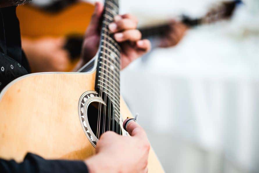 A close up of a man playing a Fado guitar.