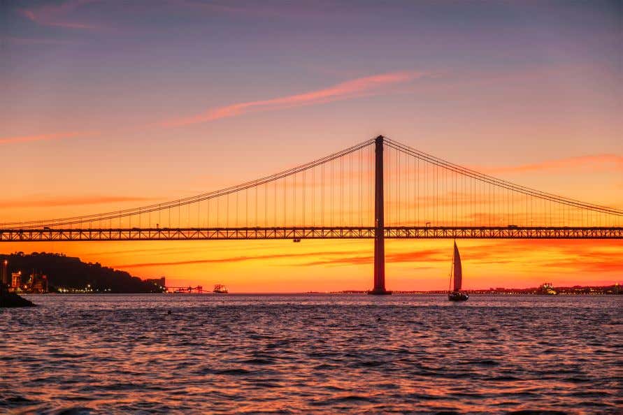 A view of the 25 de Abril Bridge over the Tagus River at sunset.