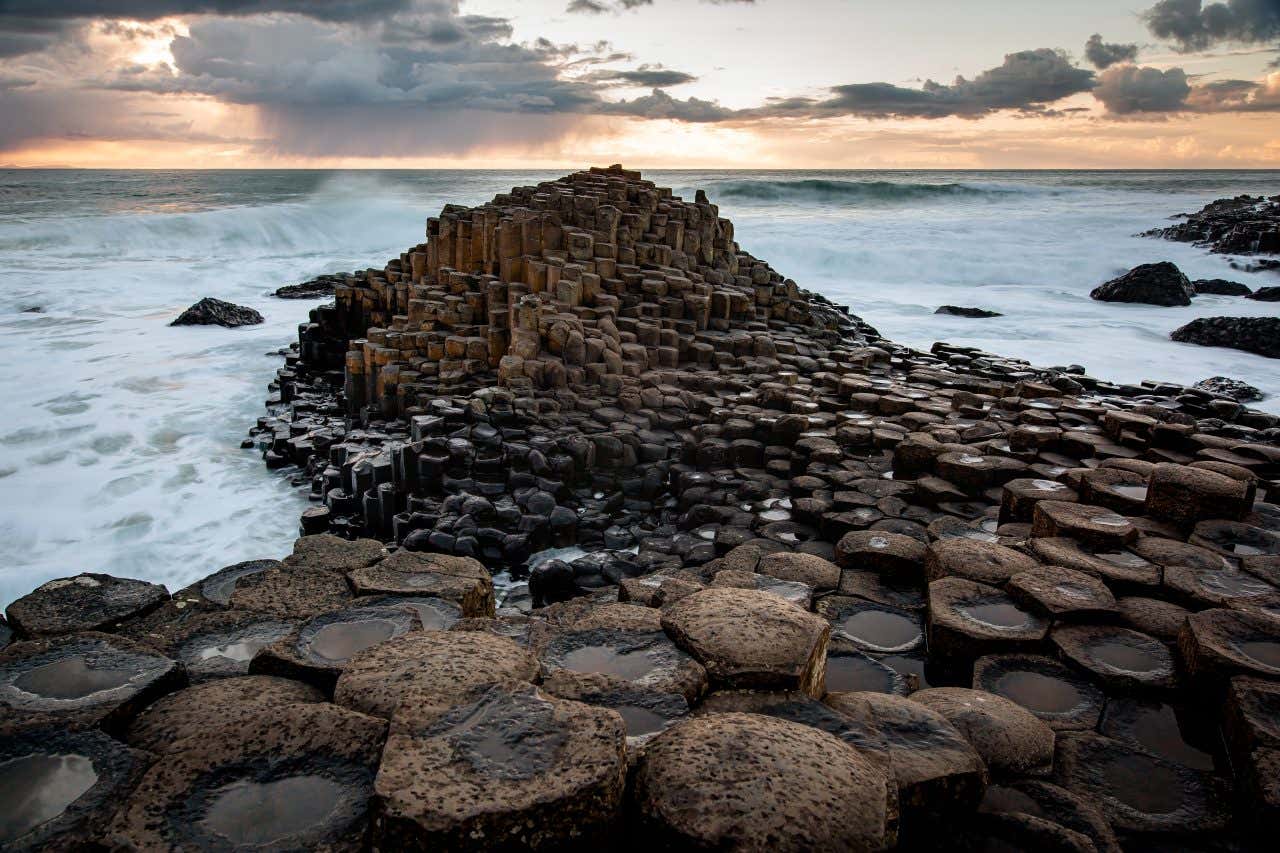 Il Giant's Causeway con il mare agitato sullo sfondo e un cielo nuvoloso