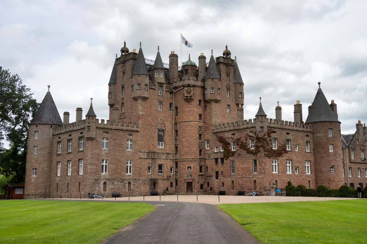 Château à l'architecture gothique et aux multiples tours sous un ciel nuageux