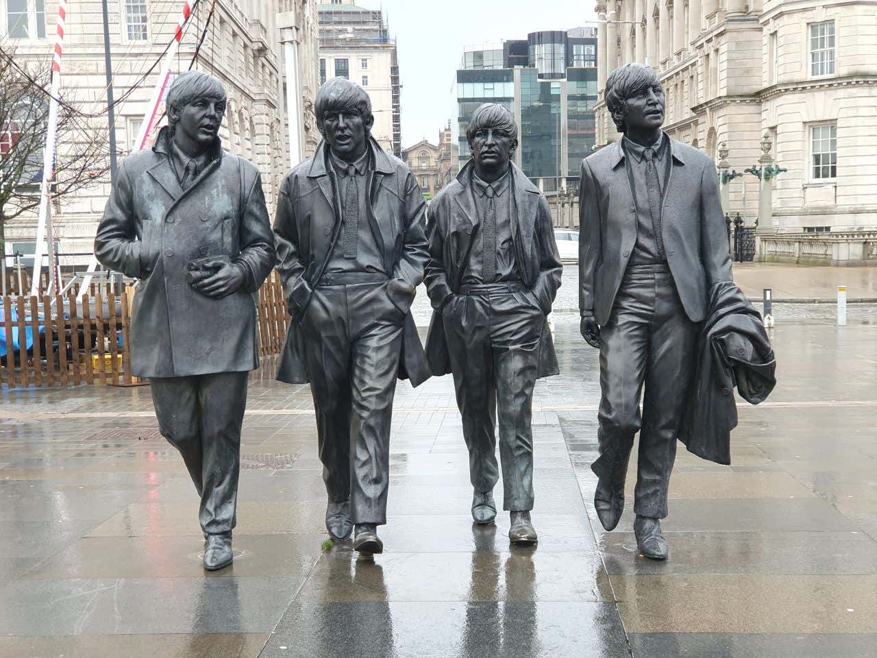 The Beatles statue in Liverpool with the city visible in the background.