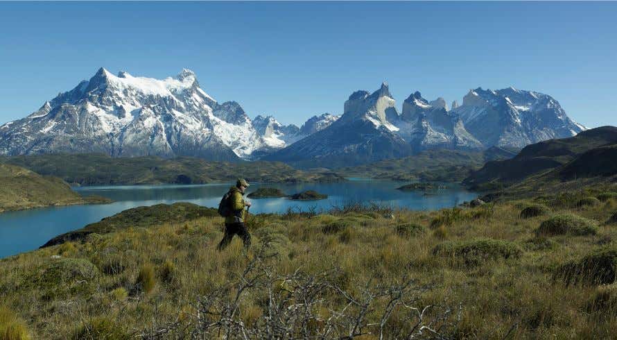 Un hombre haciendo senderismo en un valle donde se ve un valle rocoso de fondo