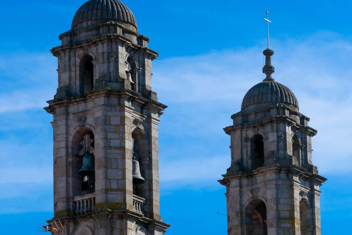 Two stone towers of a church with large bells on a clear day