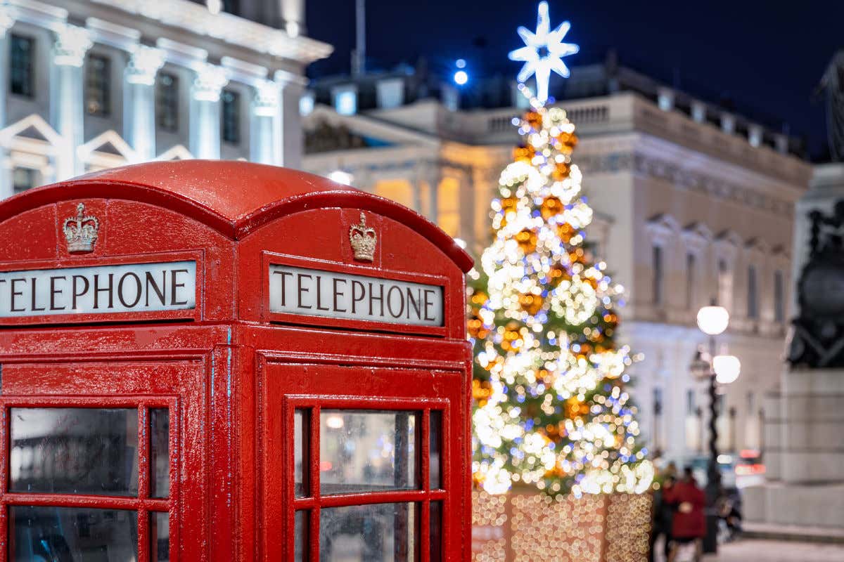 Una cabina telefónica de color rojo en Londres frente a un árbol de Navidad