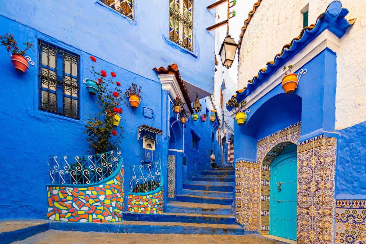 Una calle de Chefchaouen con varias casas de paredes azules y coloridos mosaicos y macetas