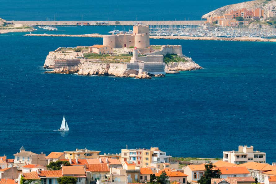 Panorámica de la isla del castillo de If, situada frente a la costa de Marsella, con un barco velero navegando por sus orillas