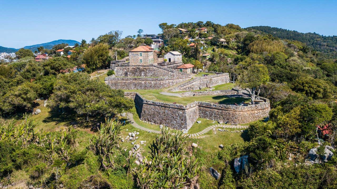 Vista panorâmica da Fortaleza de São José da Ponta Grossa rodeada de vegetação em um dia ensolarado