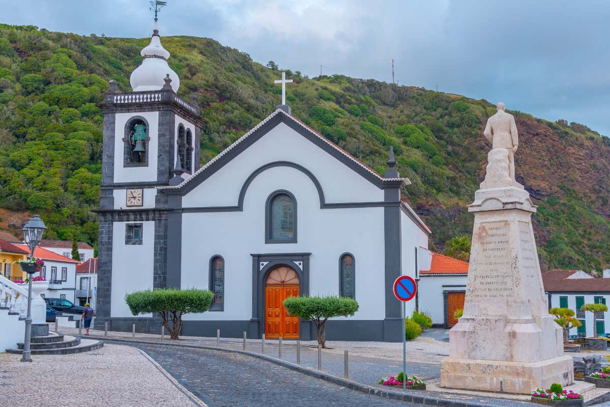 Fachada de una iglesia con una verde montaña en su parte trasera