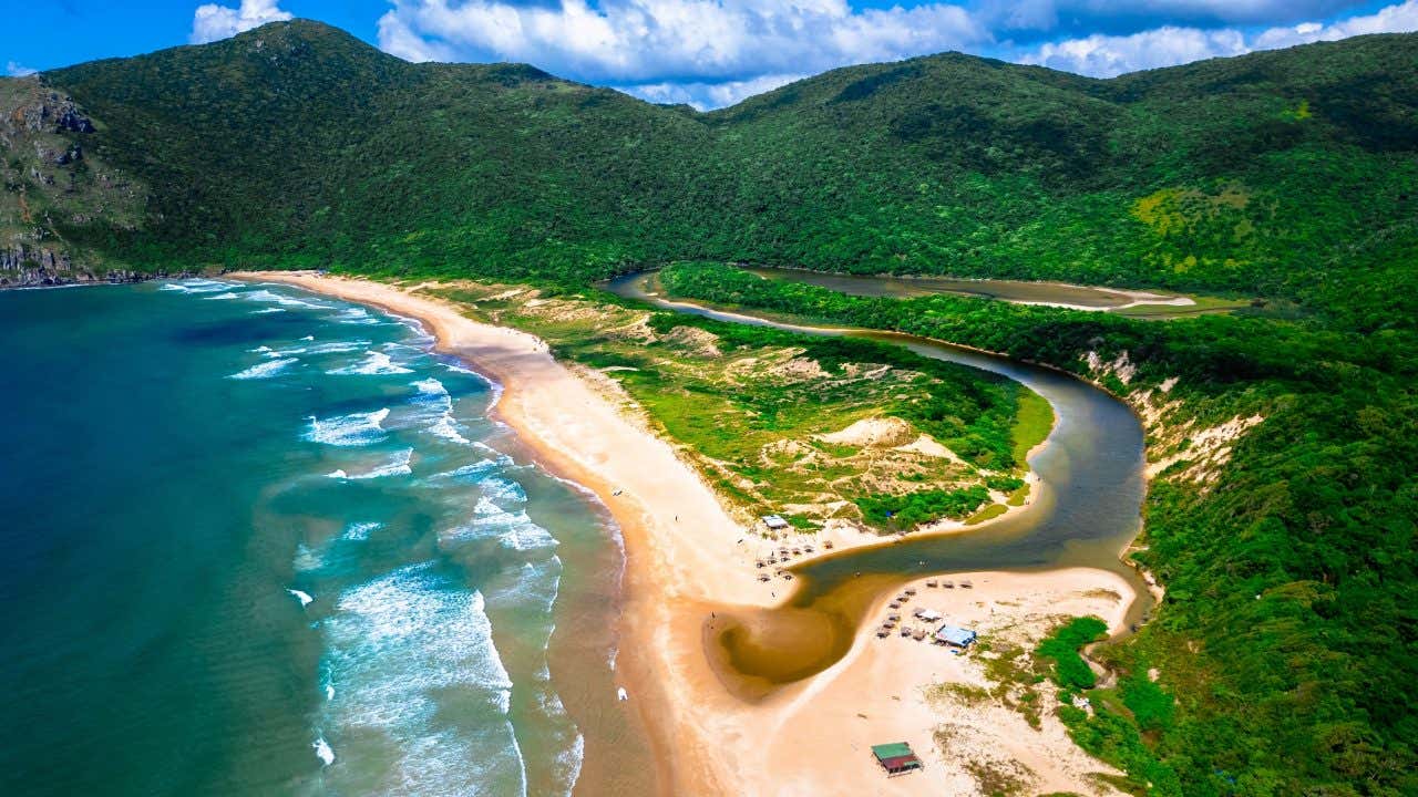 Vista aérea da paisagem natural de Lagoinha do Leste com o mar turquesa, areia dourada e frontosa vegetação