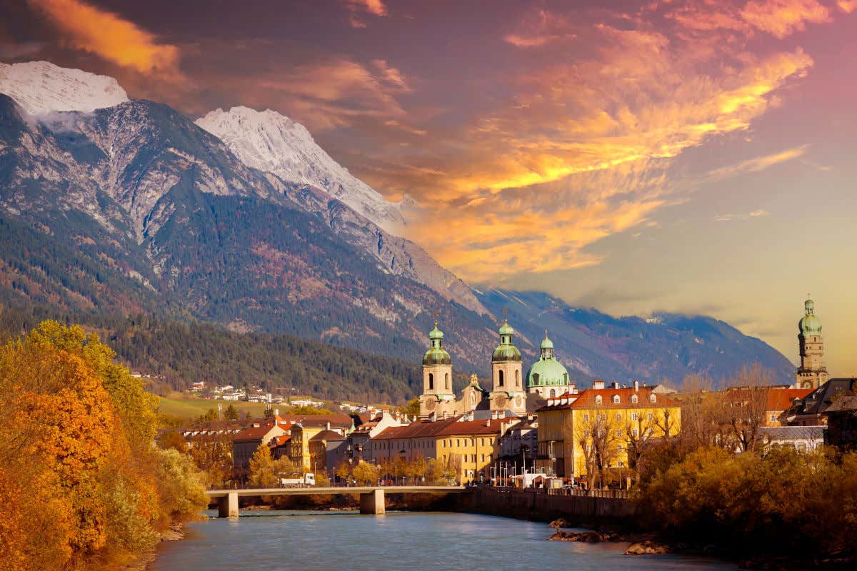 Innsbruck al atardecer, con varias montañas nevadas y las torres de una iglesia junto a un río