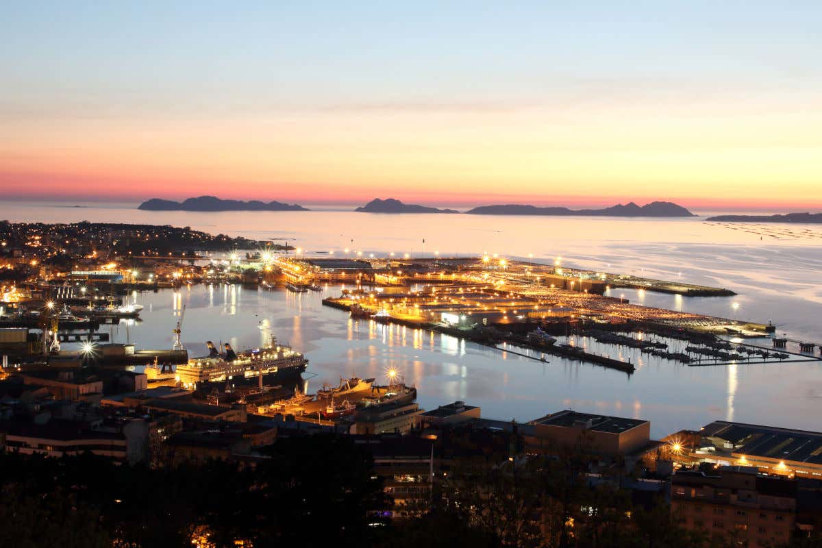 Vista aérea do porto de Vigo iluminado ao pôr do sol e com várias ilhas no horizonte