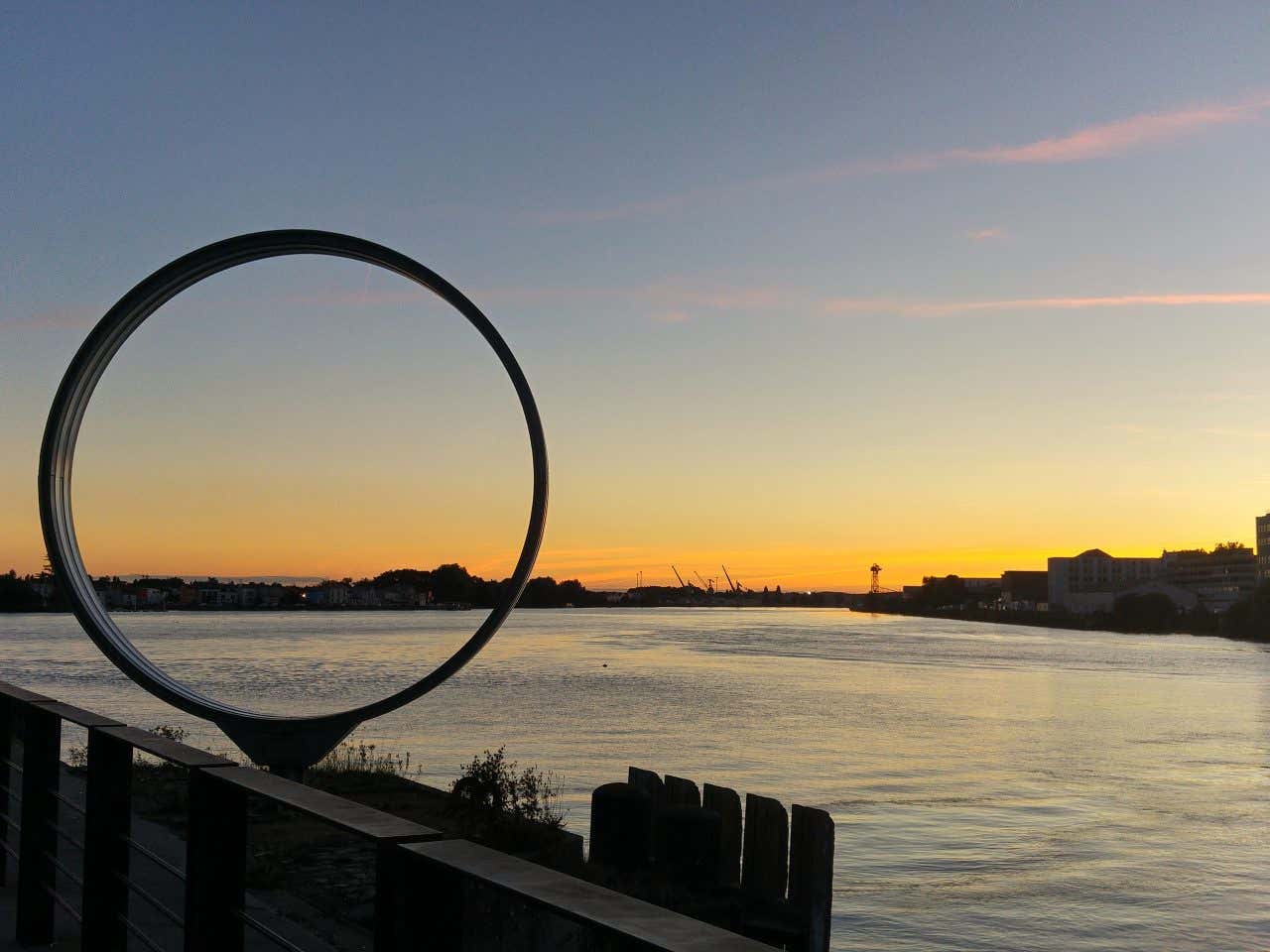 Una scultura a forma di cerchi sulle sponde di un fiume a Nantes al tramonto