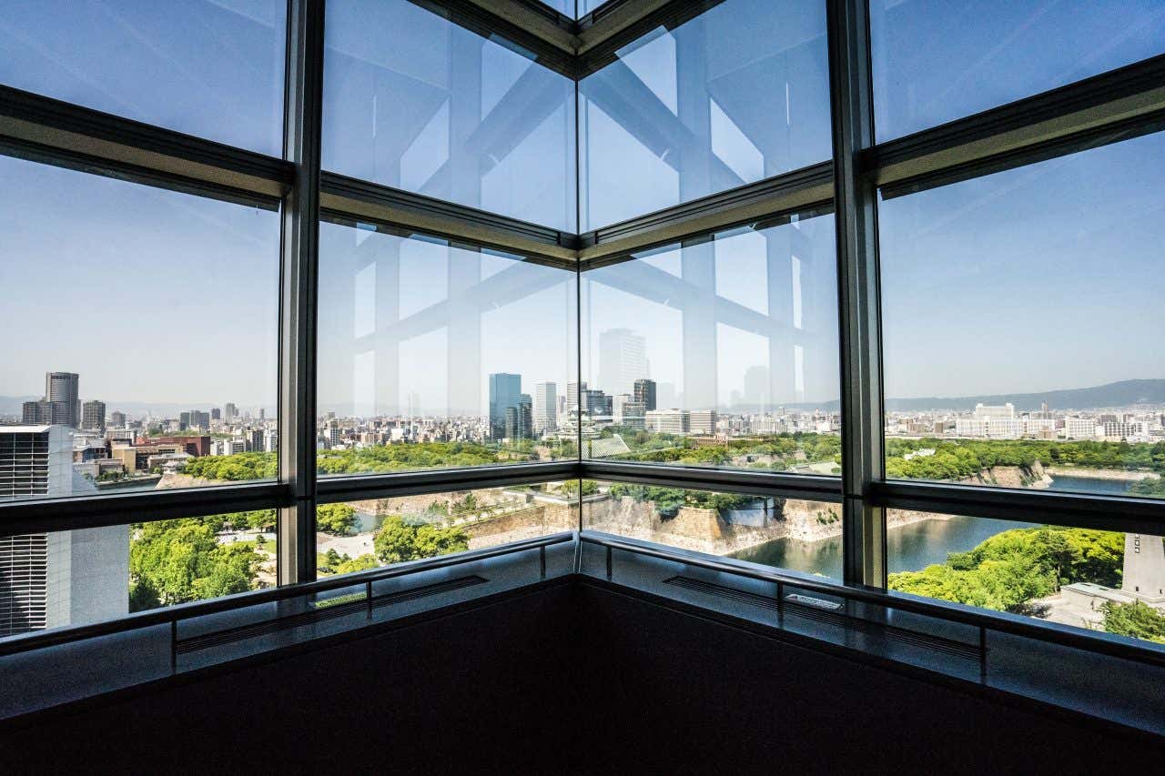 Angle d'un bâtiment avec de grandes fenêtres offrant une vue sur Osaka sous un ciel bleu