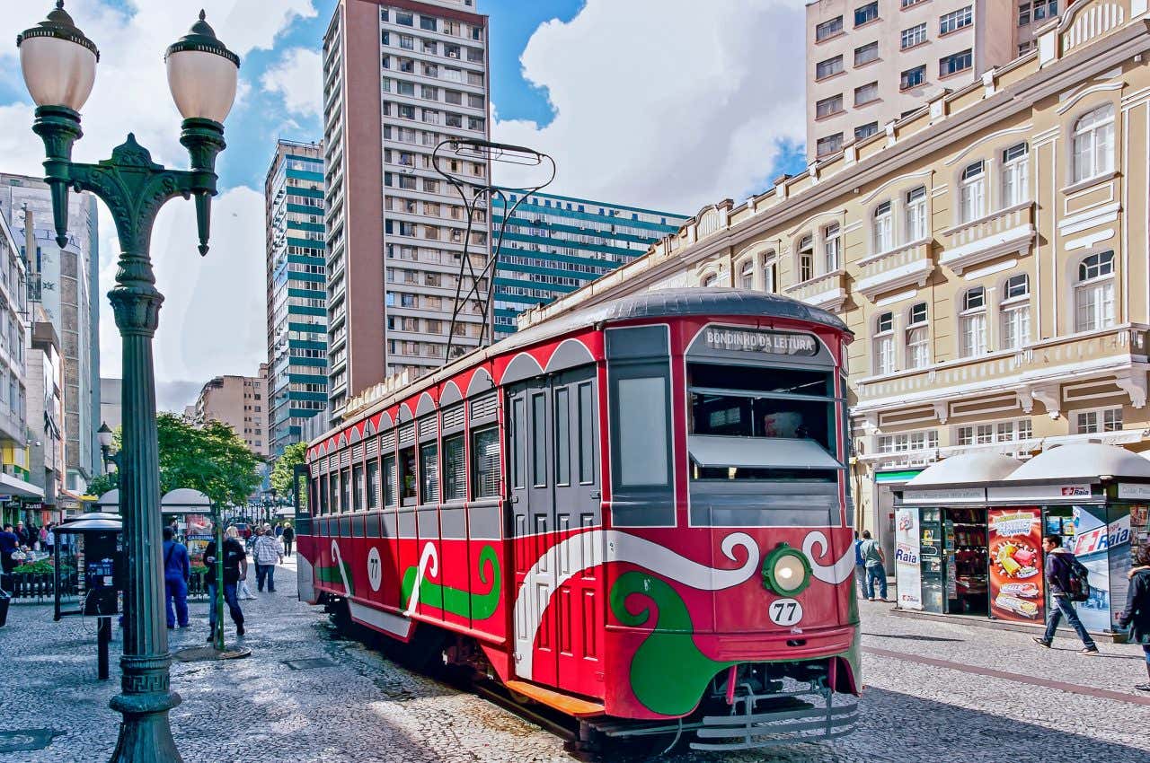 Um bonde vermelho estacionado em uma rua de pedras portuguesas