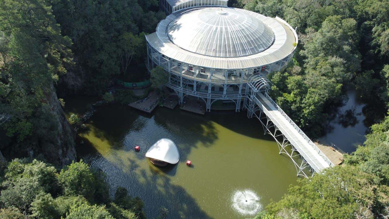 A Ópera de Arame vista de cima, rodeada de frondosa vegetação e por uma lago