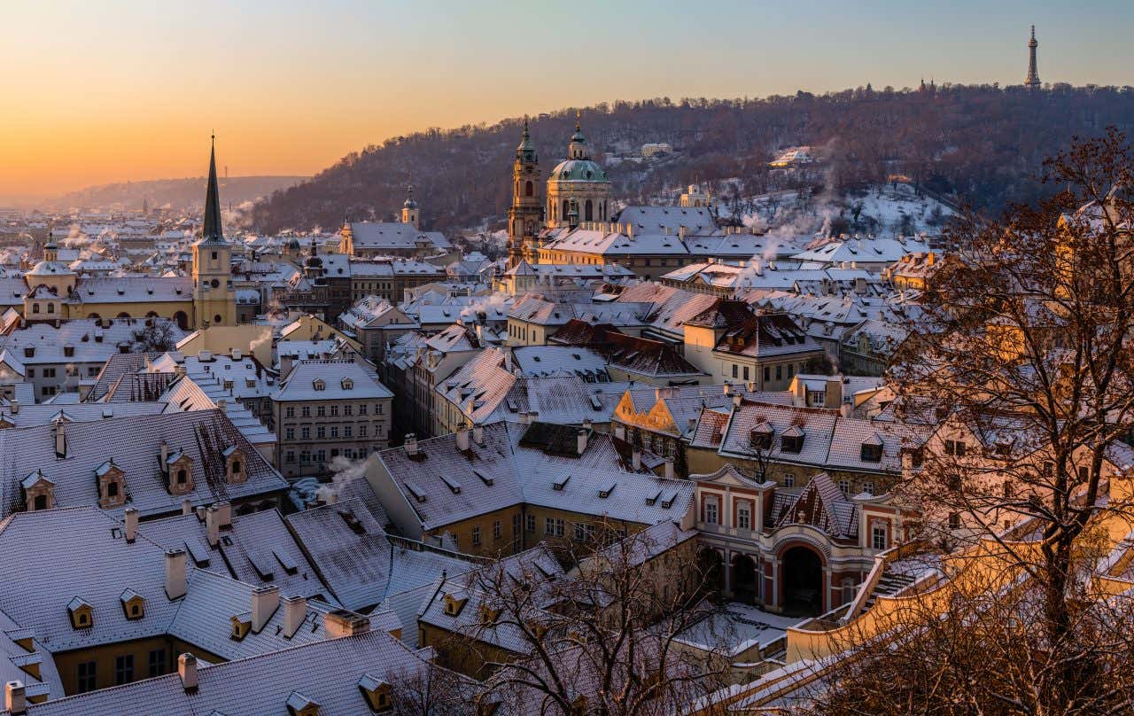 La città di Praga una fredda mattina d'inverno fotografata dall'alto. Si vedono in particolare i tetti innevati delle case e i campanili appuntiti della città