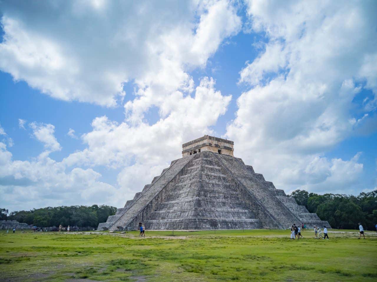 A pirâmide principal em Chichén Itzá com um céu azul nublado ao fundo.