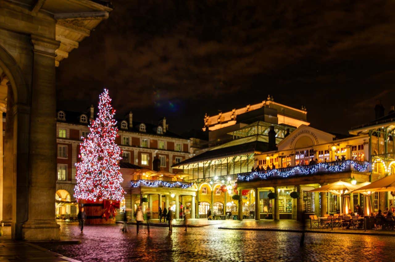 Covent Garden viewed from the outside decorated with Christmas lights and a huge Christmas tree with red lights