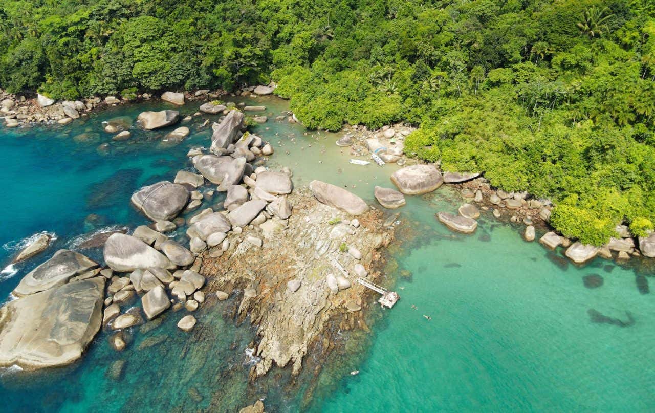 Vista aérea da piscina natural do Cachadaço rodeada de rochas que bloqueiam as ondas do oceano e pela Mata Atlântica