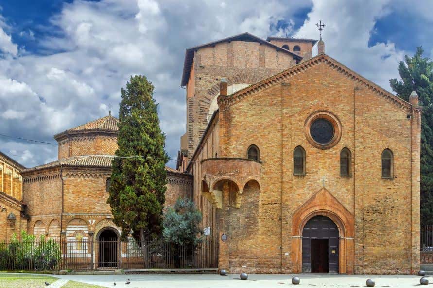 A view of the Basilica sanctuary of Santo Stefano under a blue sky with white fluffy clouds.