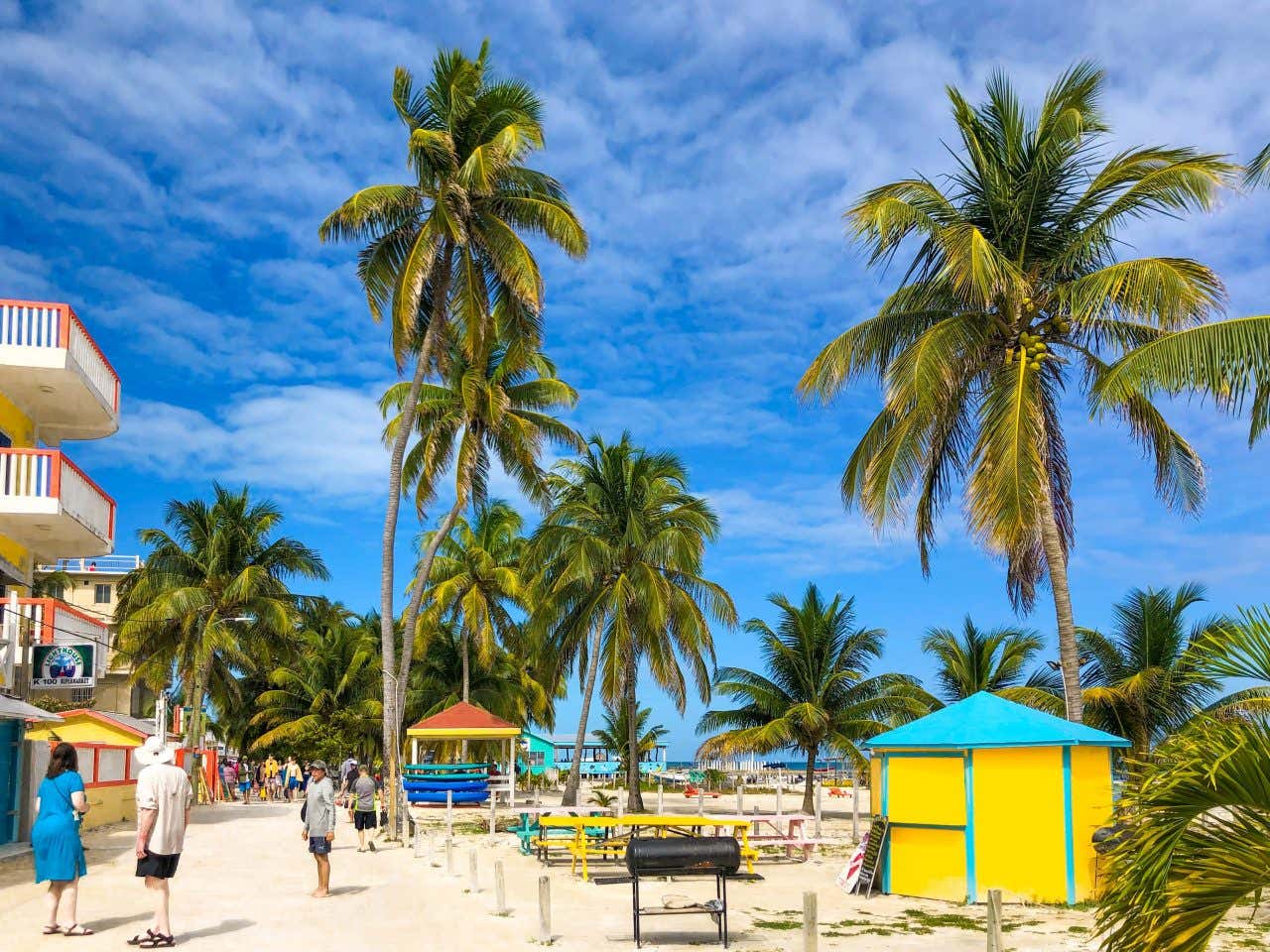 Caye Caulker town, with some palm trees, people and apartments in view.