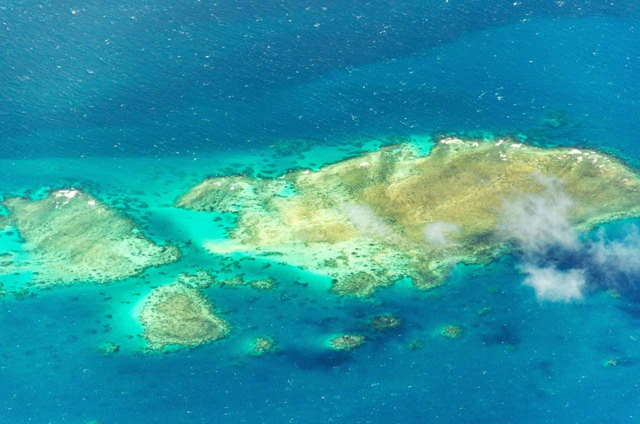 Una foto aerea che ritrae alcune macchie di scogli si percepiscono proprio sotto la superficie dell'acqua, come macchie bianche sul pelo dell'acqua in mezzo al mare turchese