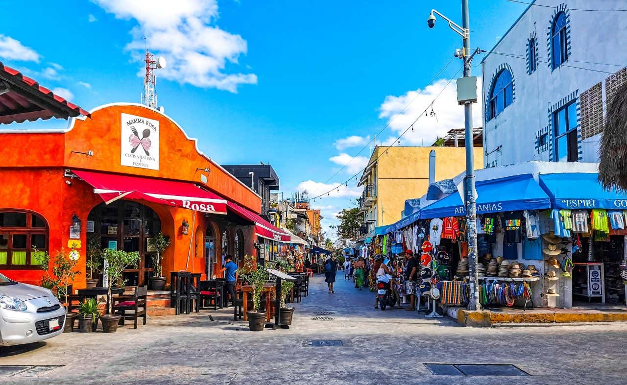 Uma rua na cidade de Cancún com várias lojas e restaurantes à vista.