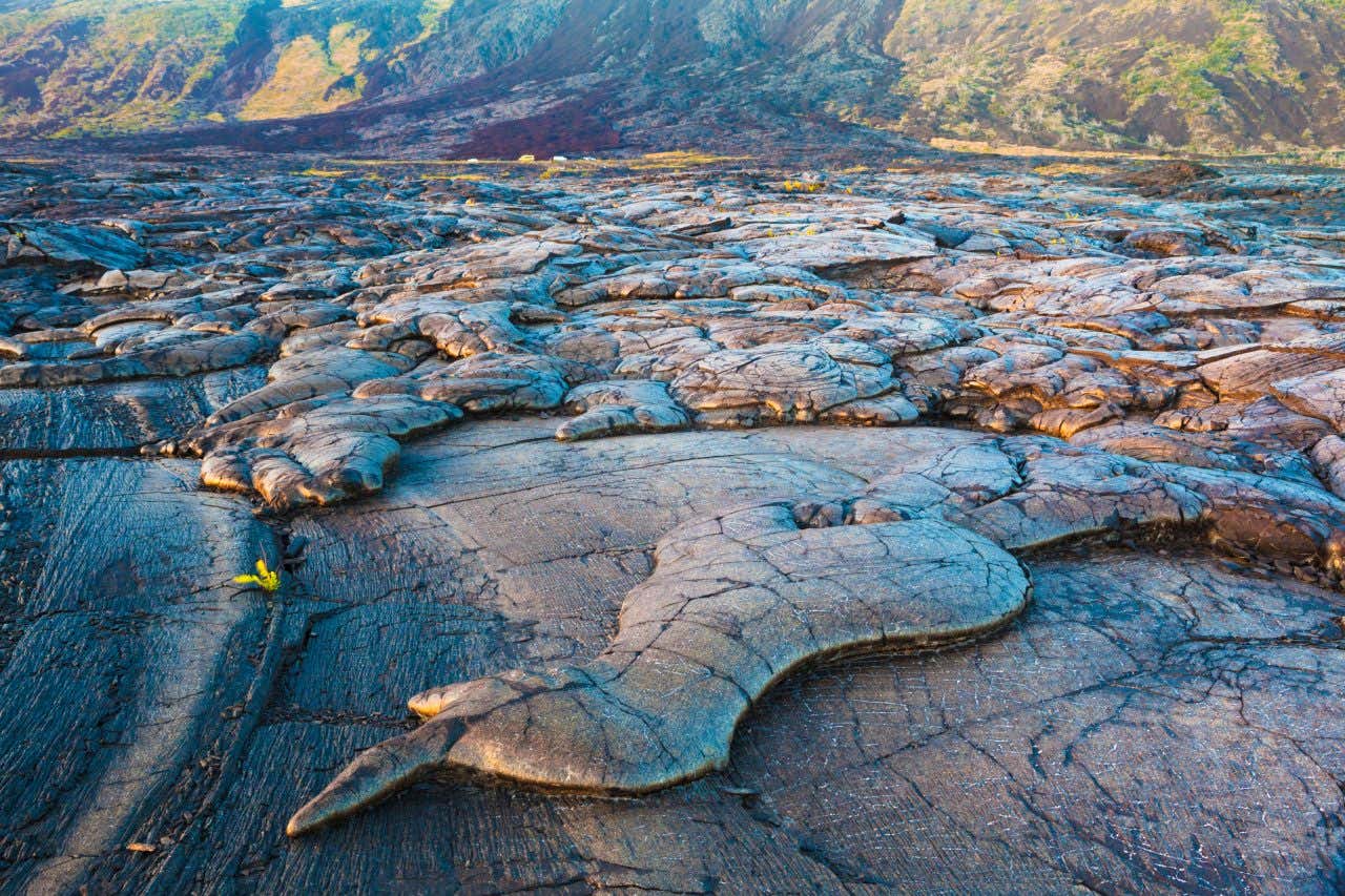 Cooled lava flow at Hawaii National Park leading the viewer to a small rising hill in the background