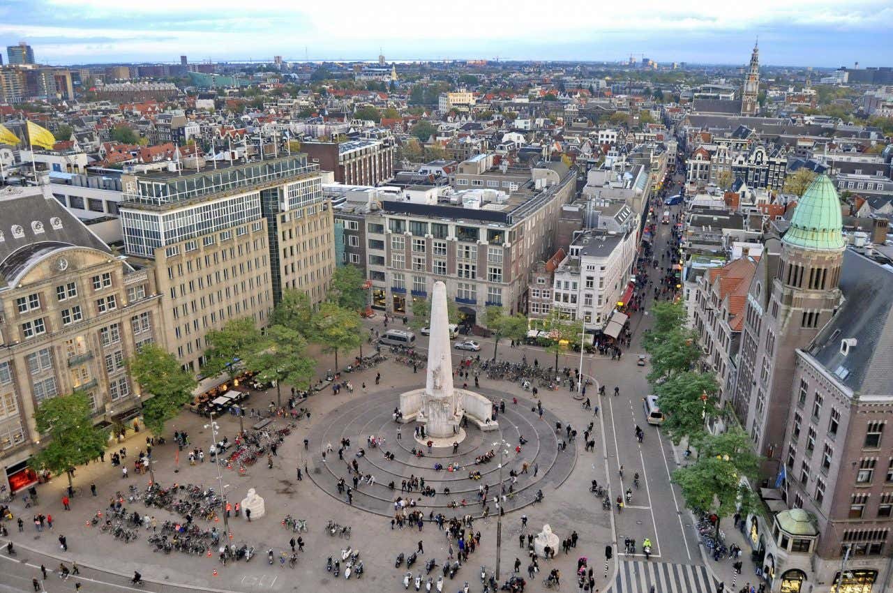 Vista aérea da Praça Dam cercada por edifícios históricos com muitas pessoas caminhando 