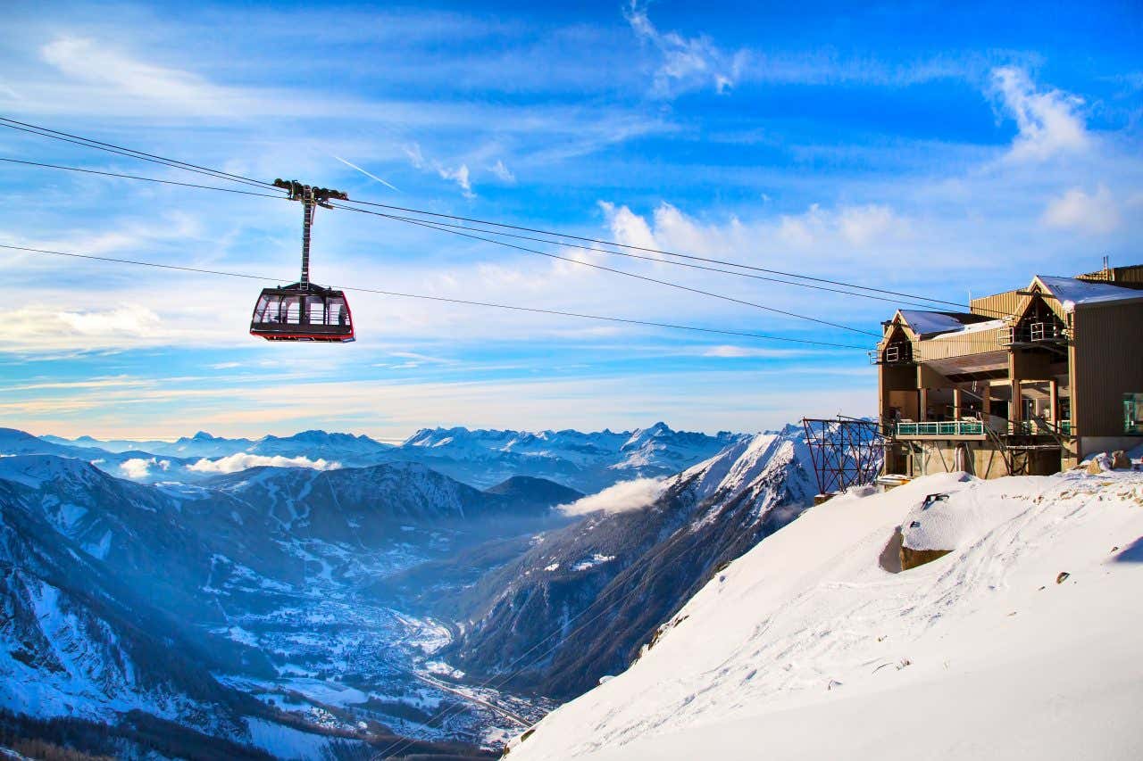 La cabina di una funivia sospesa nel vuoto poco prima di raggiungere la stazione di arriva in cima a un monte innevato