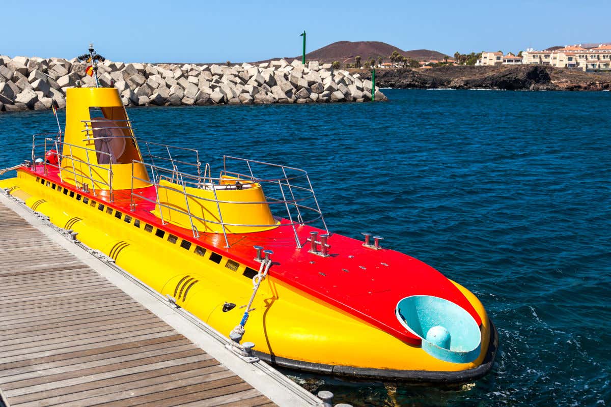 Un submarino rojo y amarillo anclado en un muelle antes de sumergirse por completo