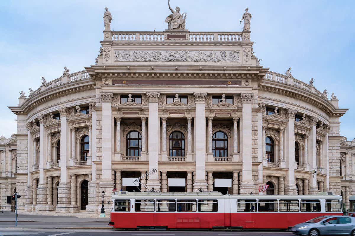 Un tranvía pasando junto a un edificio de planta circular que alberga la Ópera Estatal, uno de los monumentos más importantes que ver en Viena