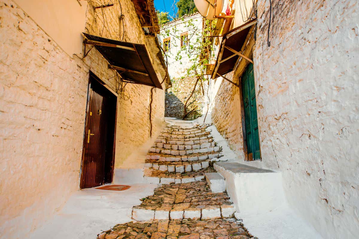 Una calle estrecha con escalones de piedra y casas de paredes blancas en la localidad de Berat