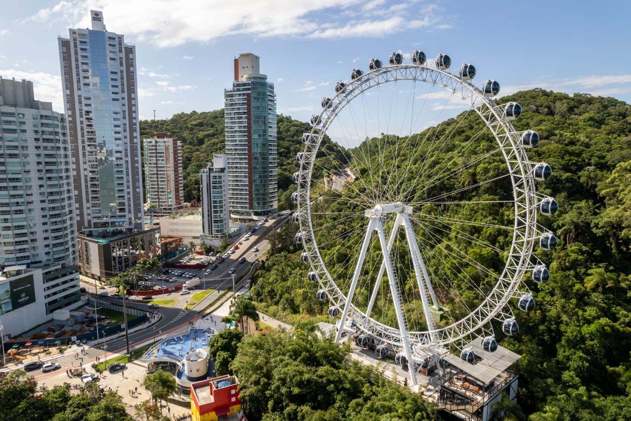 Vista aérea da roda-gigante de Balneário Camboriú ladeada por prédios altos e vegetação