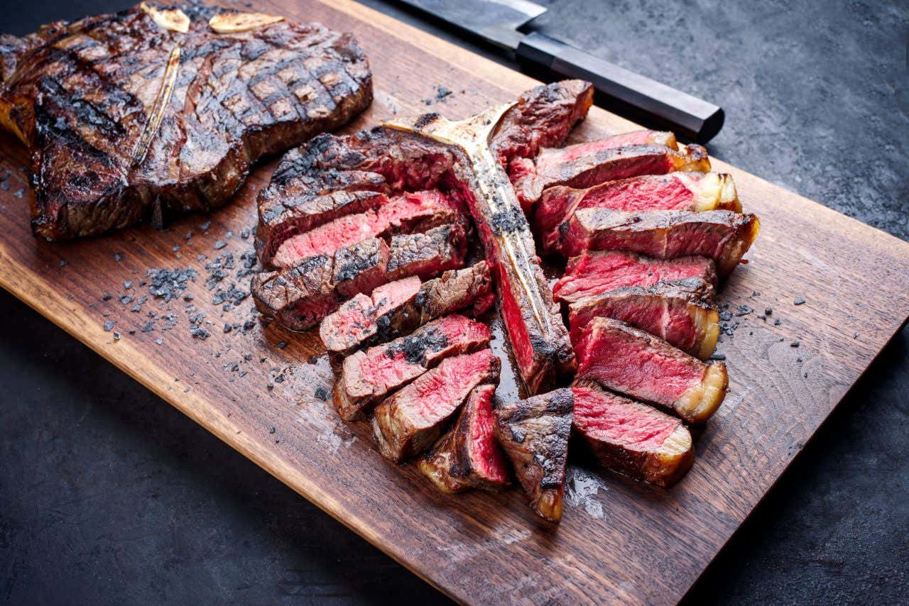 Bistecca alla Fiorentina servida ao ponto sobre uma tábua de madeira