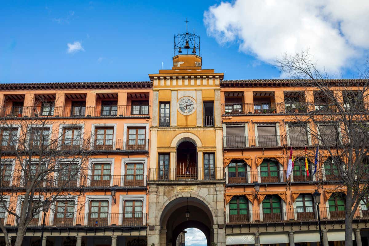 Un edificio repleto de balcones con barandillas de forja ubicado y un enorme arco de piedra en la plaza de Zocodover